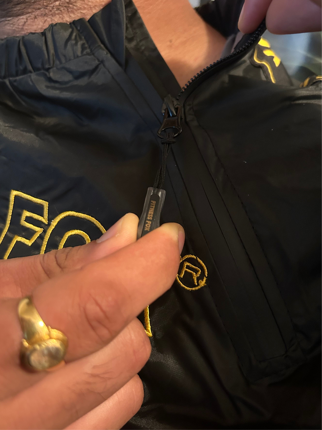 Lifestyle image of an athlete wearing the black sauna jacket with gold strip on a treadmill, reinforcing hydration, gradual duration, and safe, comfortable heat exposure.